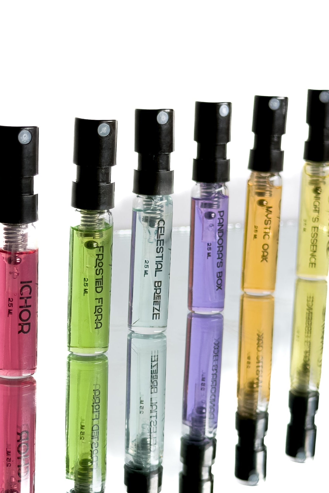 Set of small perfume bottles with colorful liquid in black caps on a white background