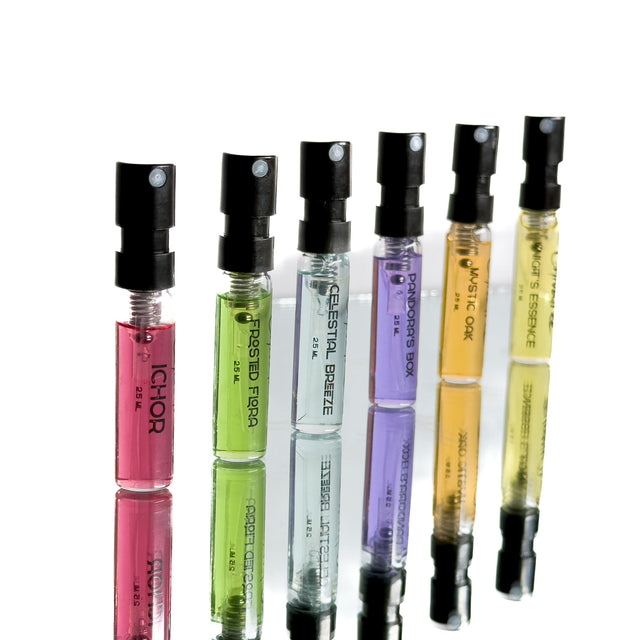 Set of small perfume bottles with colorful liquid in black caps on a white background